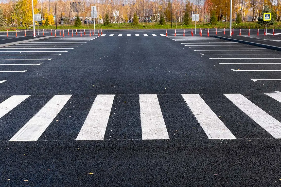 An empty parking lot featuring clearly marked white lines on a smooth asphalt surface.